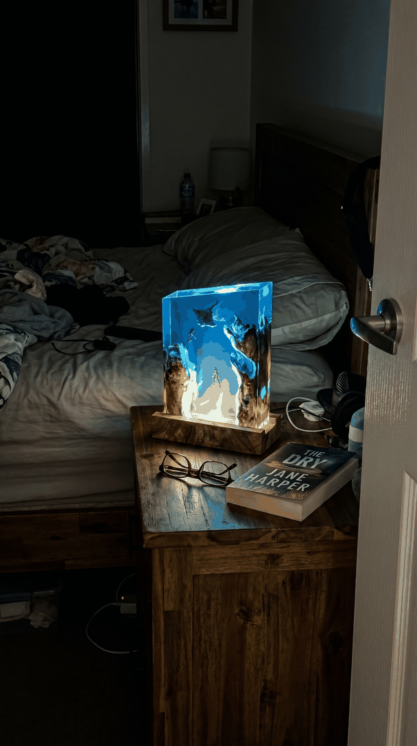 The manta lamp lit on a bedside table at night