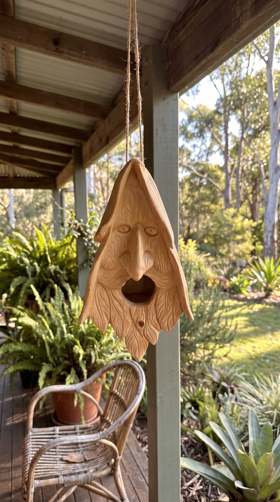 Wood spirit birdhouse hanging on a verandah