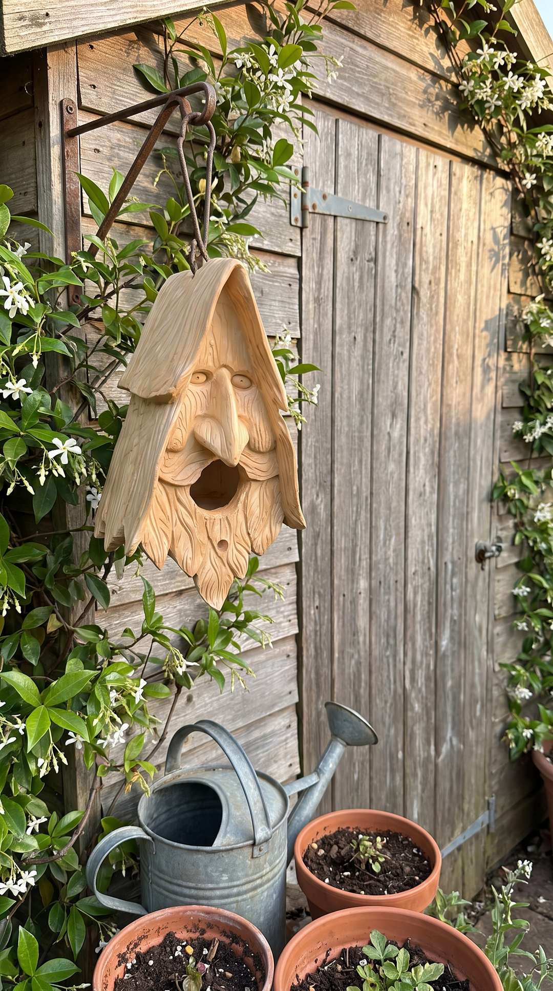 Wood spirit birdhouse beside the garden shed
