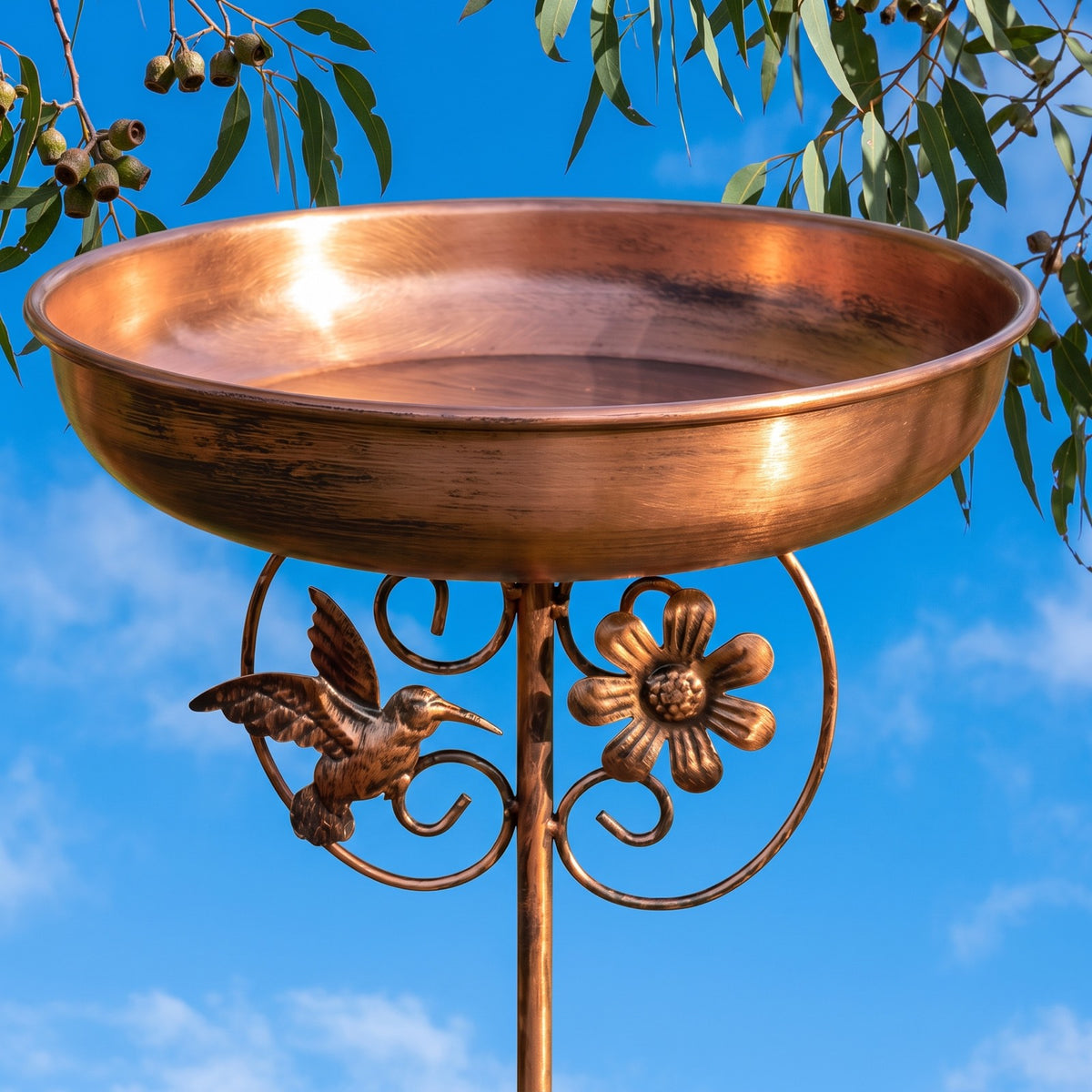 Copper bird bath from below against a blue sky