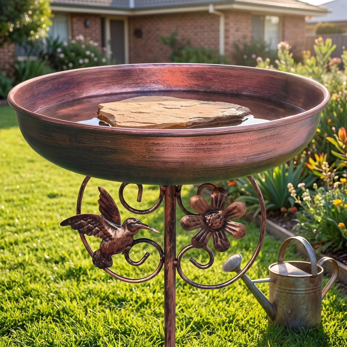 Copper bird bath on a lawn with a flat stone in the bowl