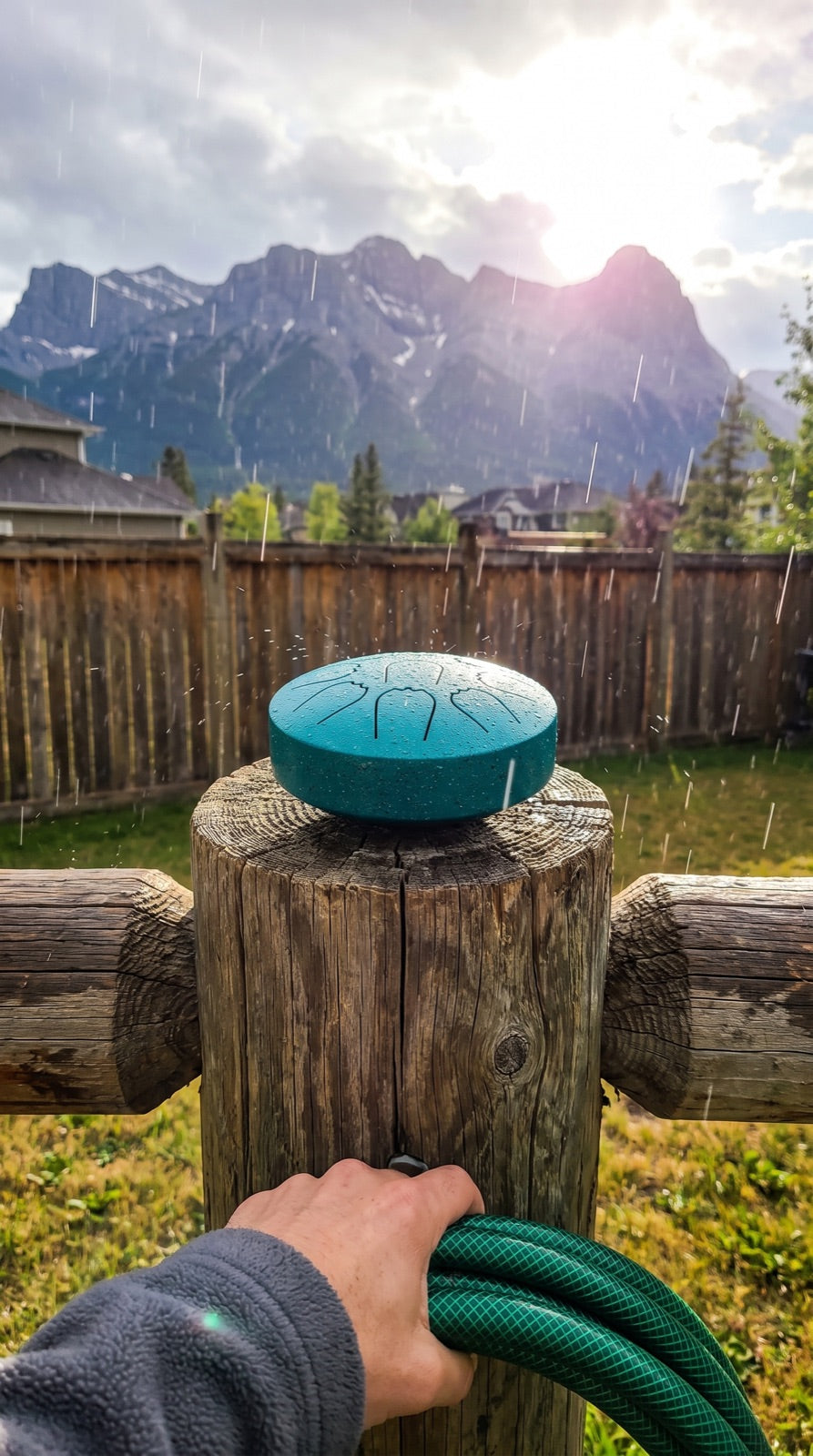 Rain drum on a fence post with the Rocky Mountains behind