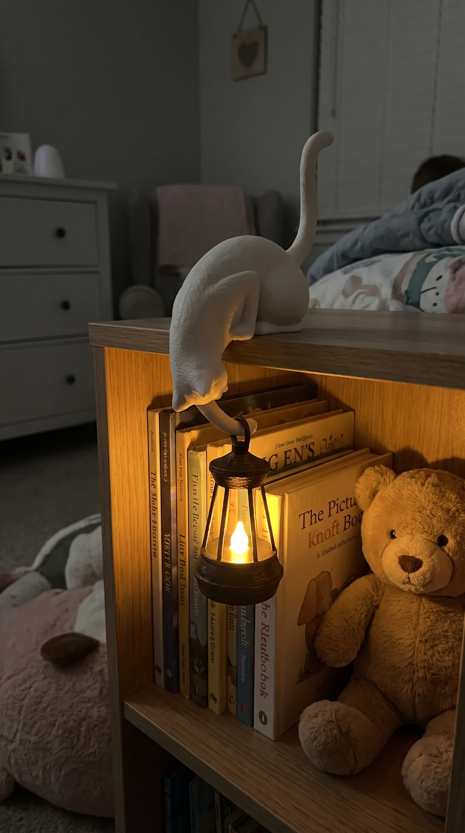 Owner photo: bone white cat lantern on a child bookcase at night