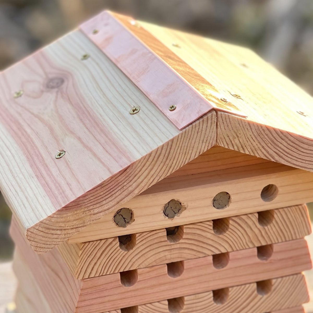 Roof detail: two thick cedar planks meeting at the ridge with brass screws and a narrow hand-folded copper flashing strip over the seam