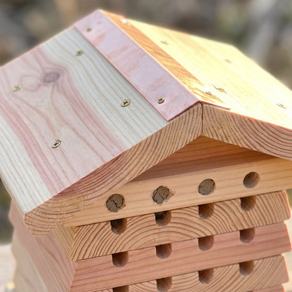 Roof detail: two thick cedar planks meeting at the ridge with brass screws and a narrow hand-folded copper flashing strip over the seam