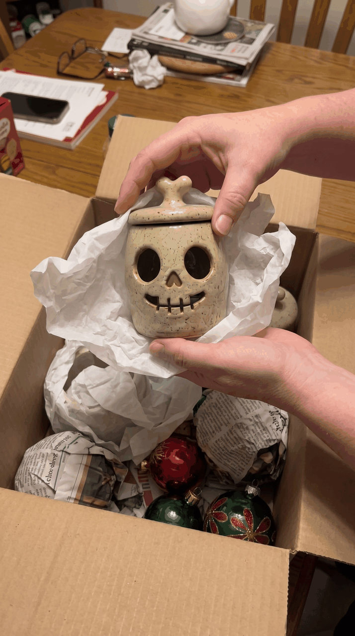 The skull lantern wrapped in tissue and packed into a box with Christmas ornaments