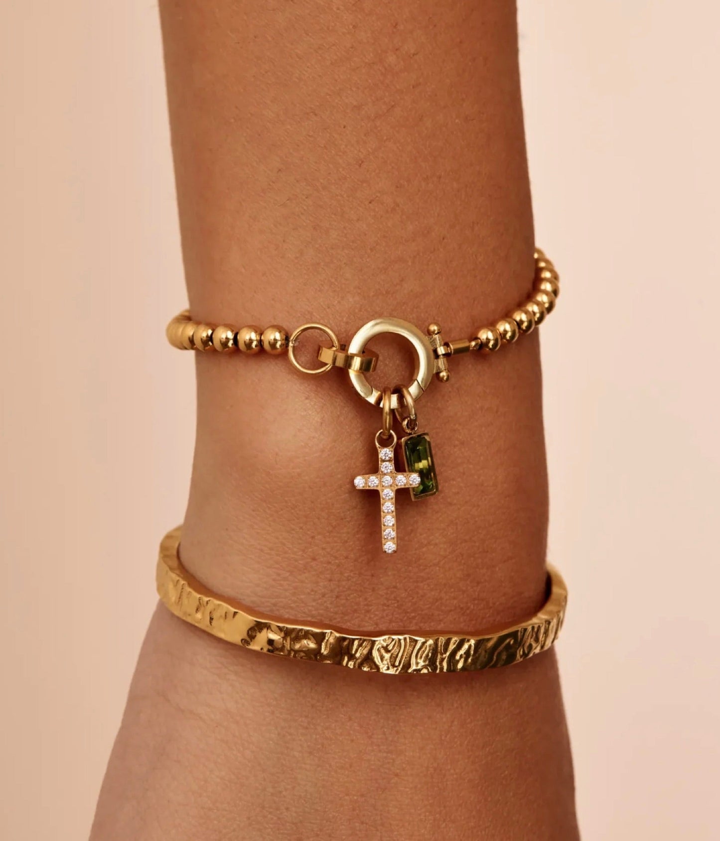 The Faith bracelet worn on a wrist — cross and birthstone charm