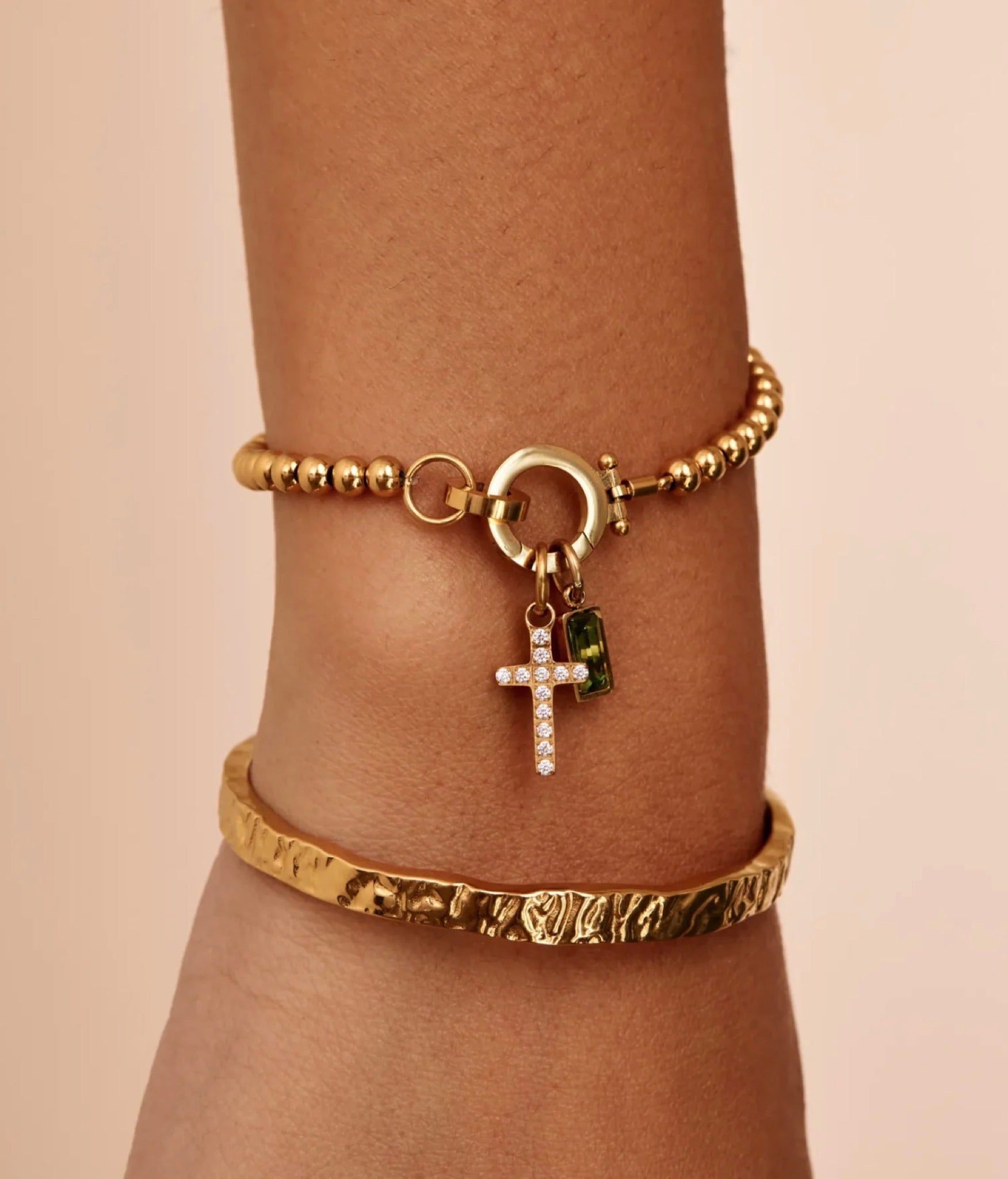 The Faith bracelet worn on a wrist — cross and birthstone charm