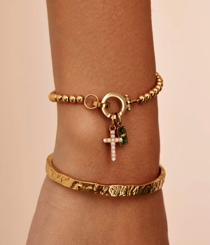 The Faith bracelet worn on a wrist — cross and birthstone charm