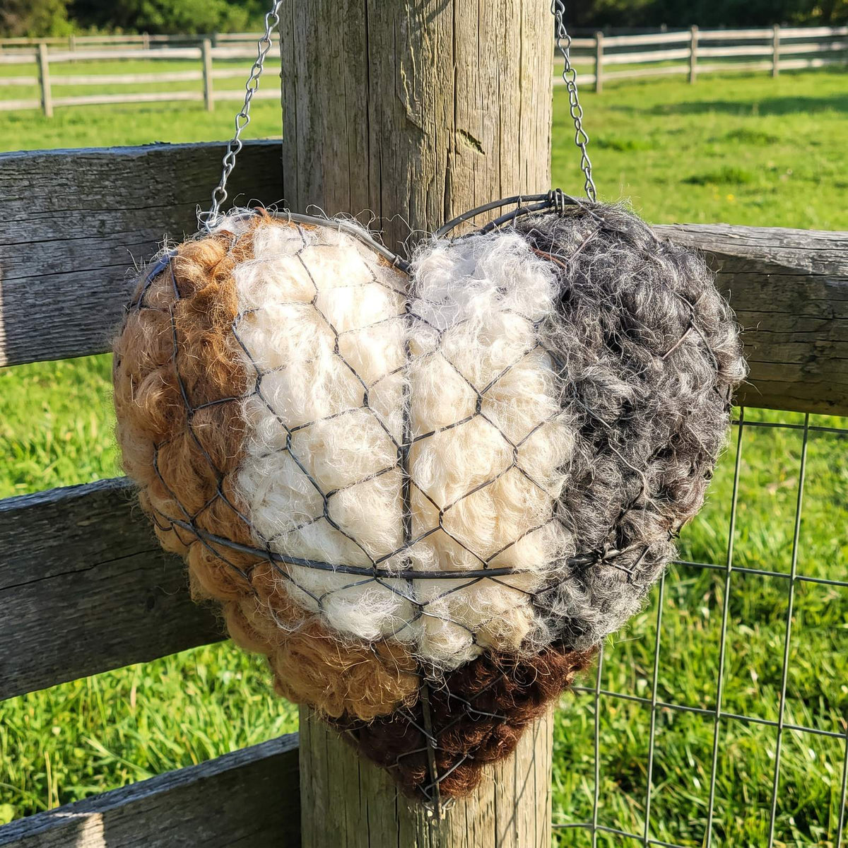 Alpaca nesting heart hanging from a weathered fence post