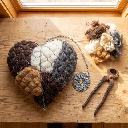 Alpaca nesting heart on a timber table with fleece and fencing pliers