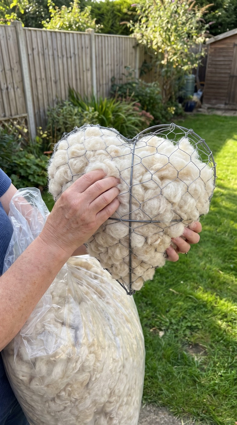 Hands refilling the nesting heart with fresh alpaca fleece