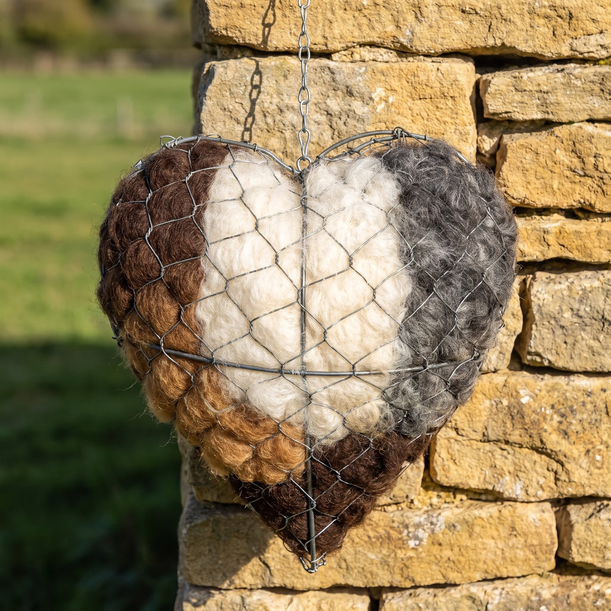 Sylvia's Alpaca Nesting Heart hanging on a Cotswold drystone wall