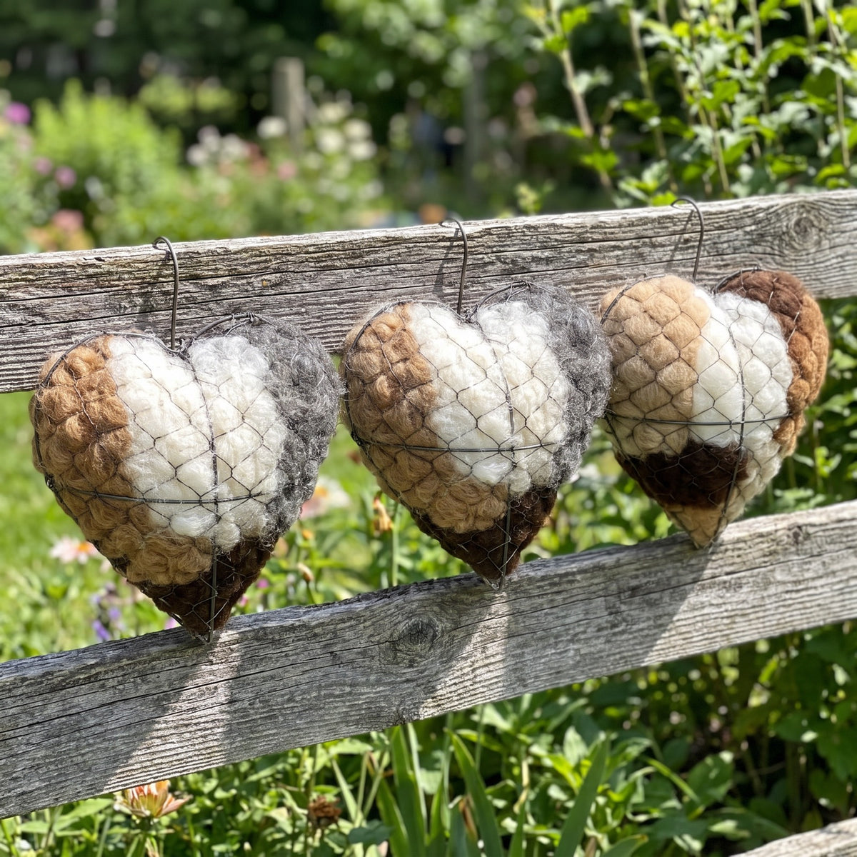 Three nesting hearts hanging in a row on a garden rail